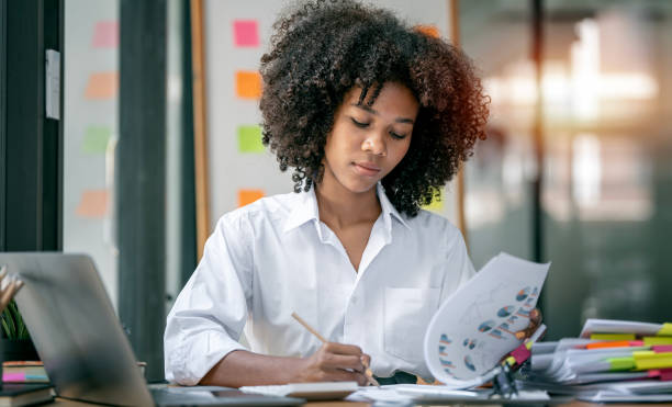 Attractive young african american business woman working on business graph chart, analysing research finance